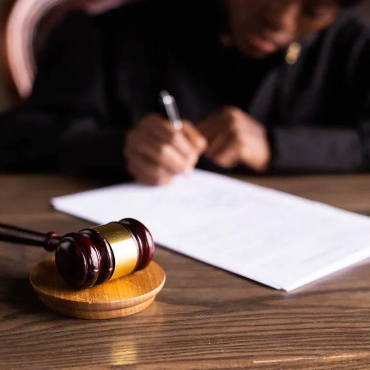 Judge signing a legal document, gavel in foreground